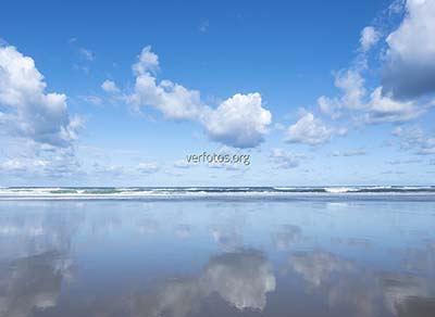 Las nubes del cielo se reflejan en el mar y la playa 
