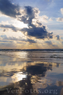 Al atardecer en la playa, el sol se oculta tras las nubes, reflejando colores vibrantes sobre el mar en la costa, Ciudad de Donostia-San Sebastián.